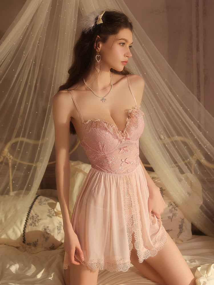 Woman wearing a pink lace nightgown in a softly lit room with a canopy.