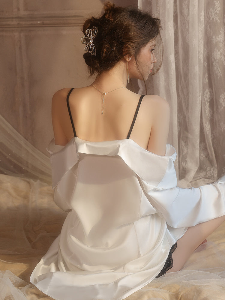 Woman in a white satin robe sitting on a bed with a neutral background