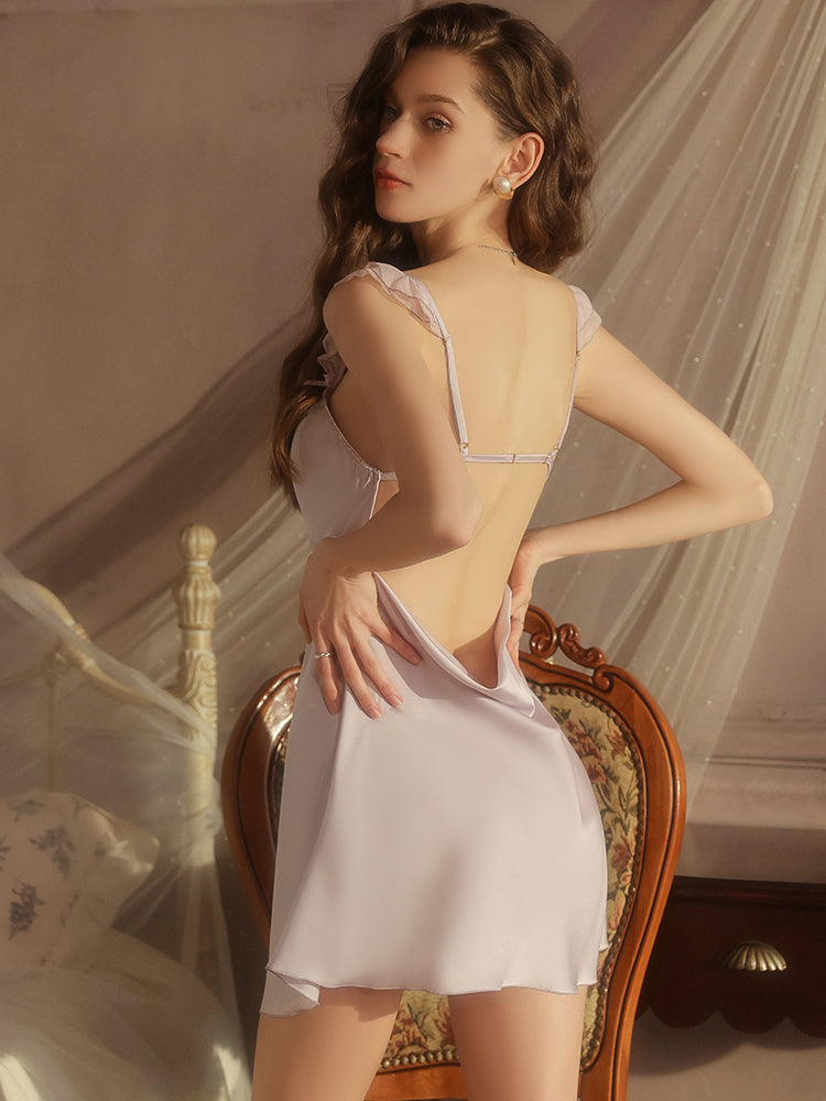Woman wearing a white lace nightgown in a softly lit room.