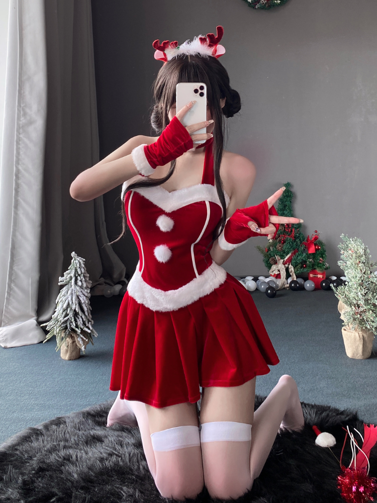 Halter mini costume dress with fur trim details, sleeveless design, and velvet fabric, styled with festive accessories in a cozy indoor setting.