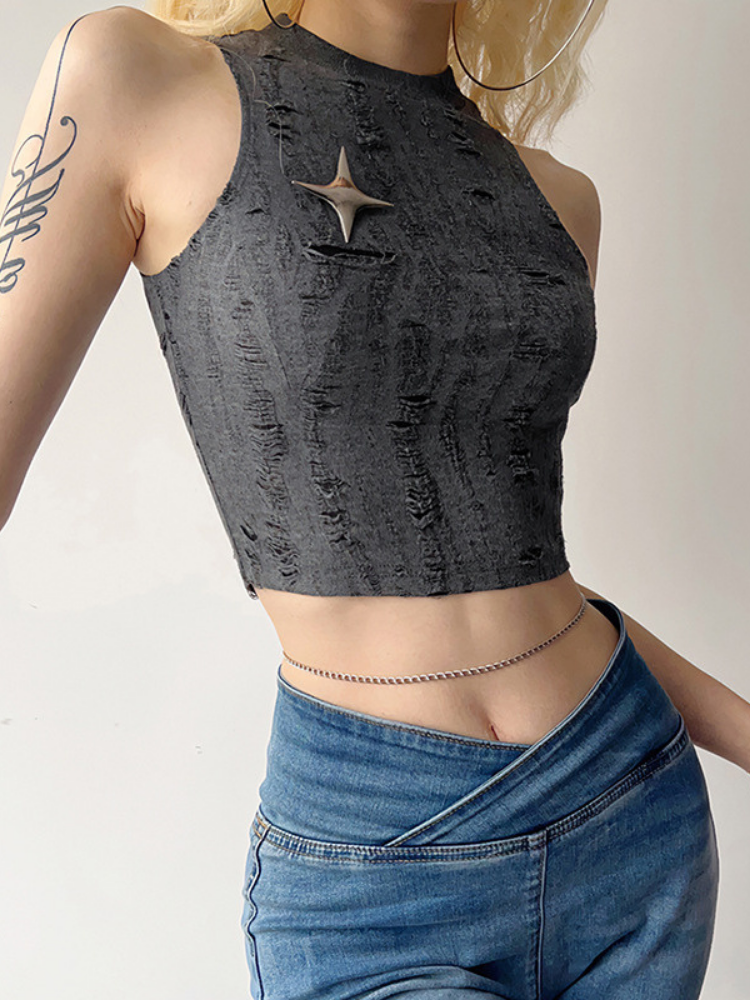 Person wearing a black distressed crop top and blue jeans on a plain background