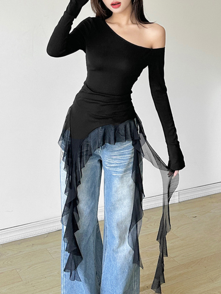 Person wearing a black off-shoulder top and blue jeans with ruffled layers on a plain background