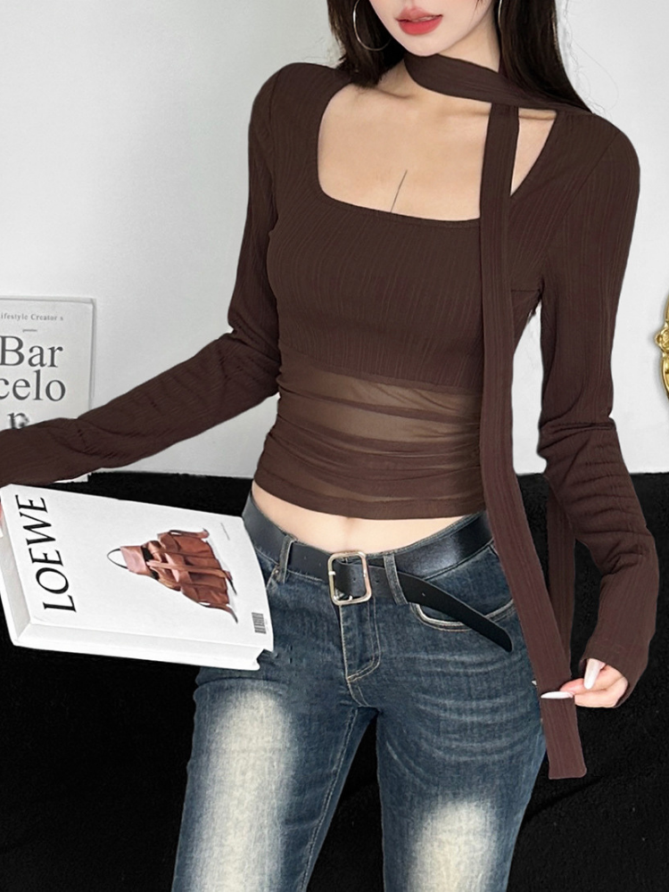 Person wearing a brown long-sleeve top and jeans, holding a magazine with visible branding.