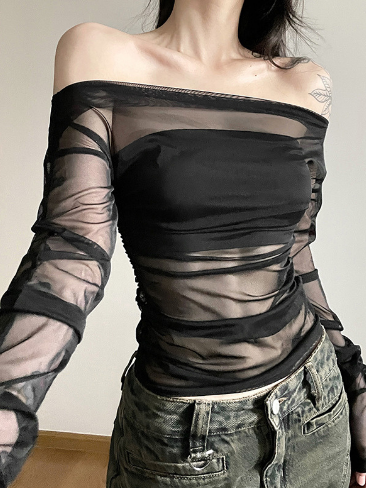 Person wearing a black off-shoulder top with sheer sleeves against a neutral background