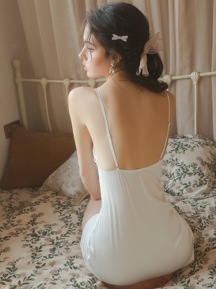 Woman in a white dress sitting on a bed with floral bedding