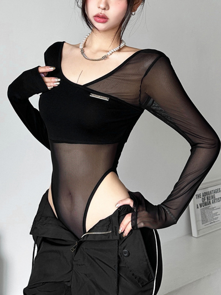 Person wearing a black sheer top with long sleeves and high cut sides on a plain background.