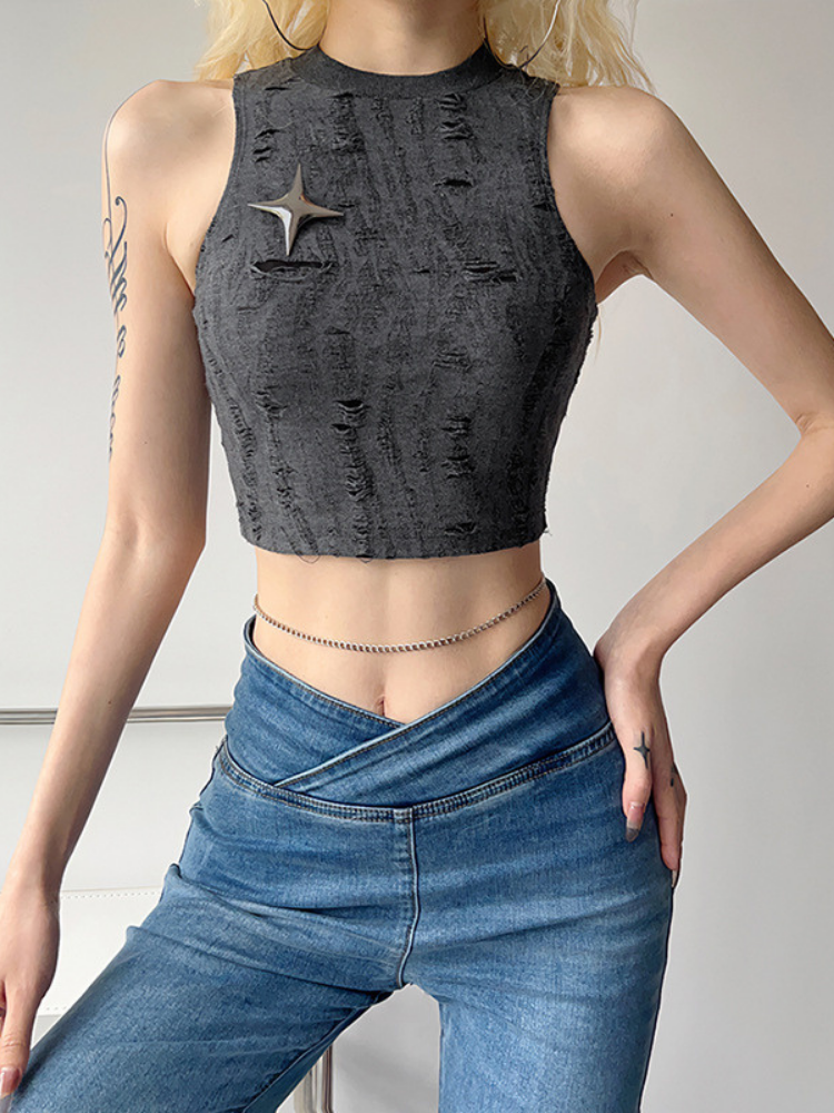 Person wearing a distressed black tank top and blue jeans against a neutral background