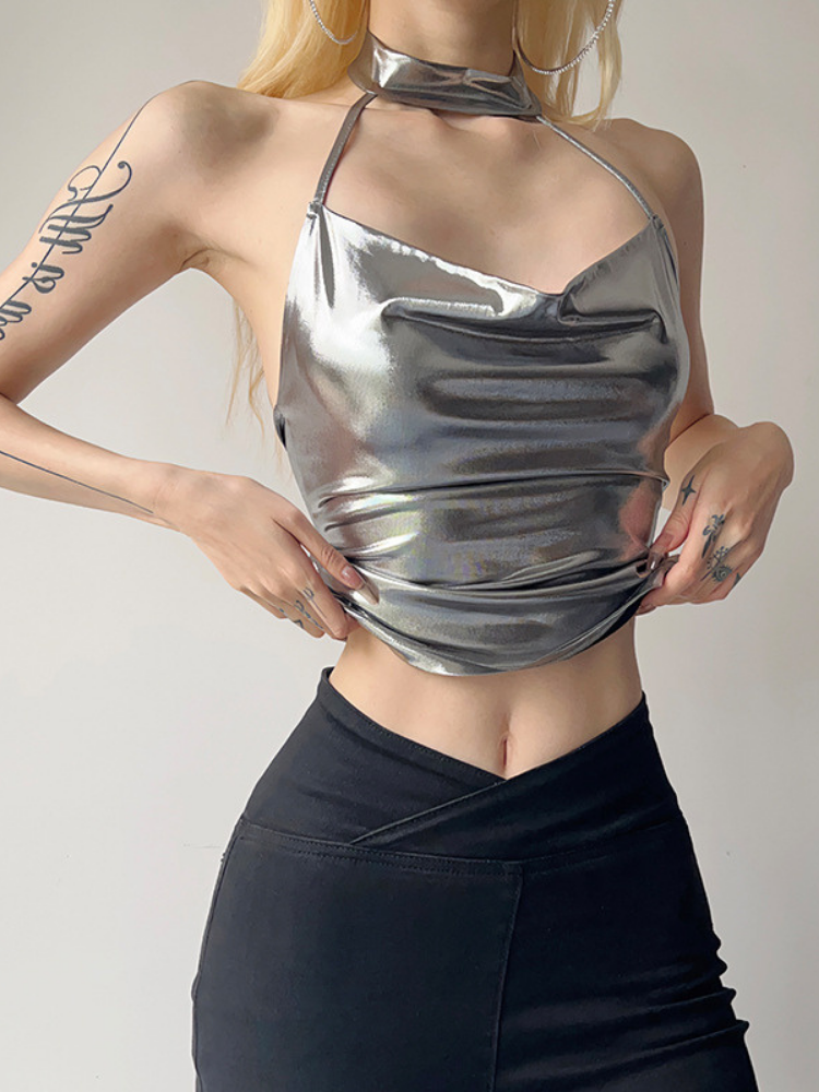 Person wearing a metallic silver halter top and black pants on a plain background