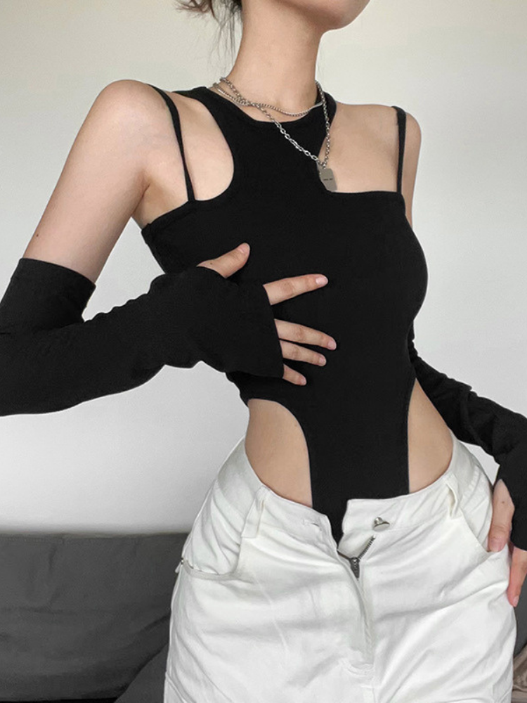 Person wearing a black sleeveless top with cut-out design and white pants against a neutral background