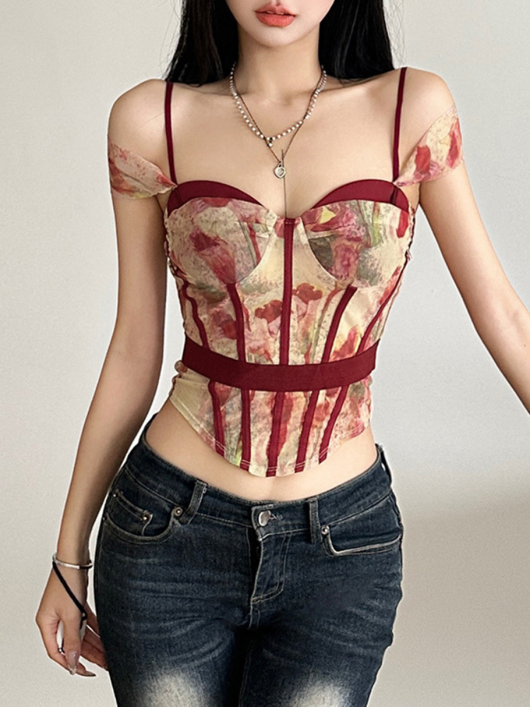 Woman wearing a patterned corset top and jeans against a plain background