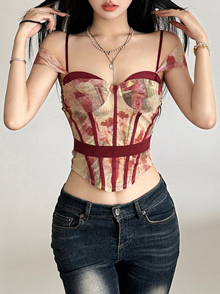 Woman wearing a floral corset over a sheer top with dark jeans.