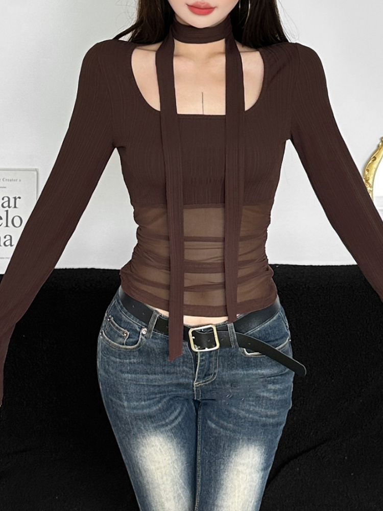 Person wearing a brown long-sleeve top with mesh panels and blue jeans on a white background