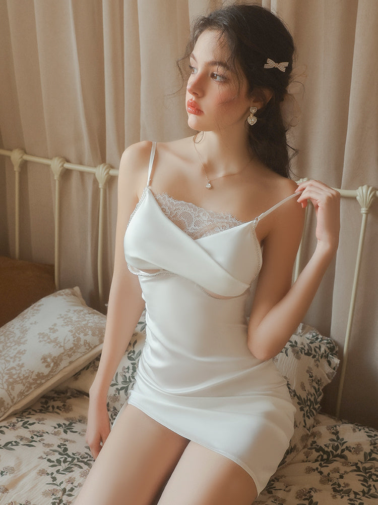 Woman wearing a white lace nightgown sitting on a bed with floral bedding.