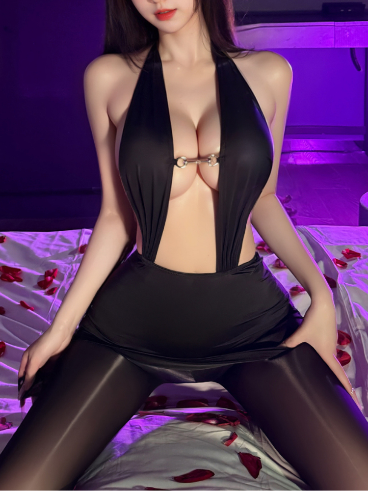 Woman in a Plunge Halter Ring Detail Black Mini Dress Bodysuit sitting on a bed with purple lighting