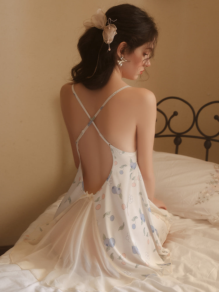 Woman in a floral nightgown sitting on a bed with a neutral background