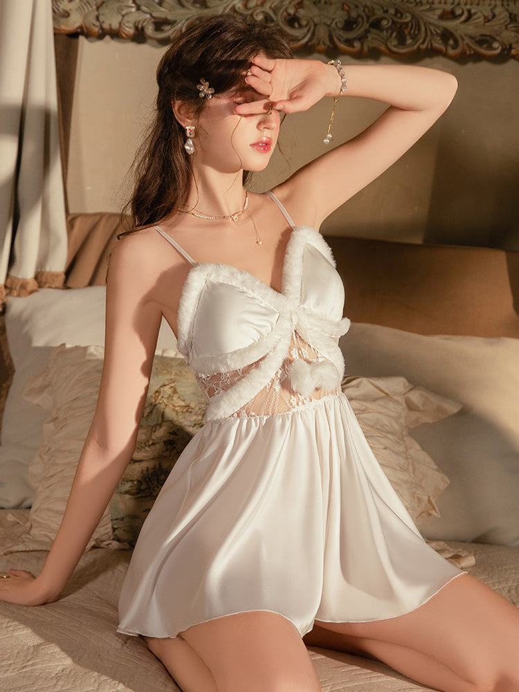 Woman in a White Satin Faux Fur Slip Dress sitting on a bed with a warm, soft light.