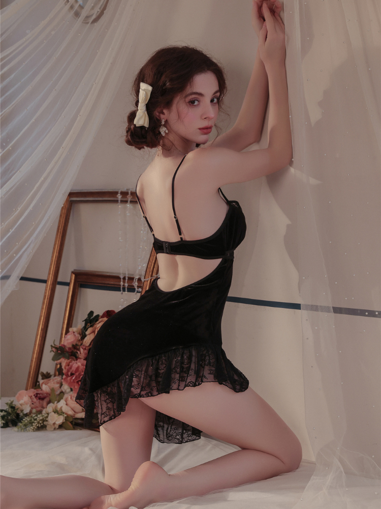 Woman in a black Velvet Lace Cutout Spaghetti Strap Slip Dress posing in a softly lit room with white curtains and flowers.