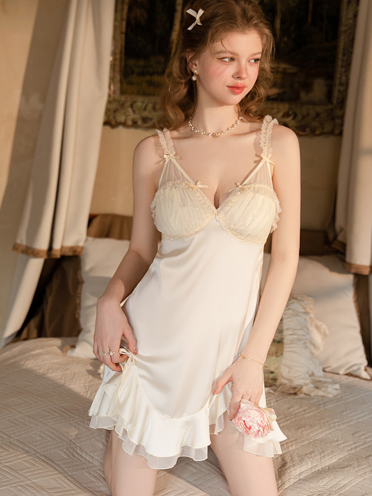 Woman wearing a vintage-style cream lace nightgown in a softly lit room. satin mini dress, slip dress, babydoll dress, white slip dress, open back dress, ruffle mini dress, lace trim sleep dress.