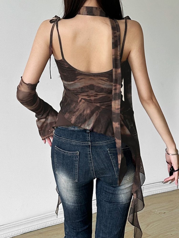 Person wearing a sheer brown top and blue jeans against a plain background