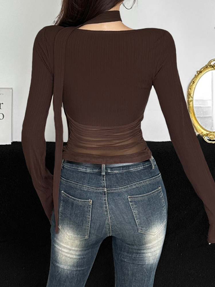 Person wearing a brown long-sleeve top and blue jeans from behind, with a white wall and gold-framed mirror in the background.