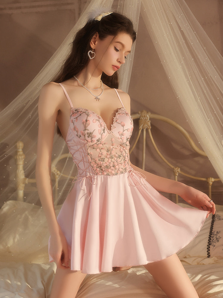 Woman wearing a pink floral nightgown in a softly lit bedroom.