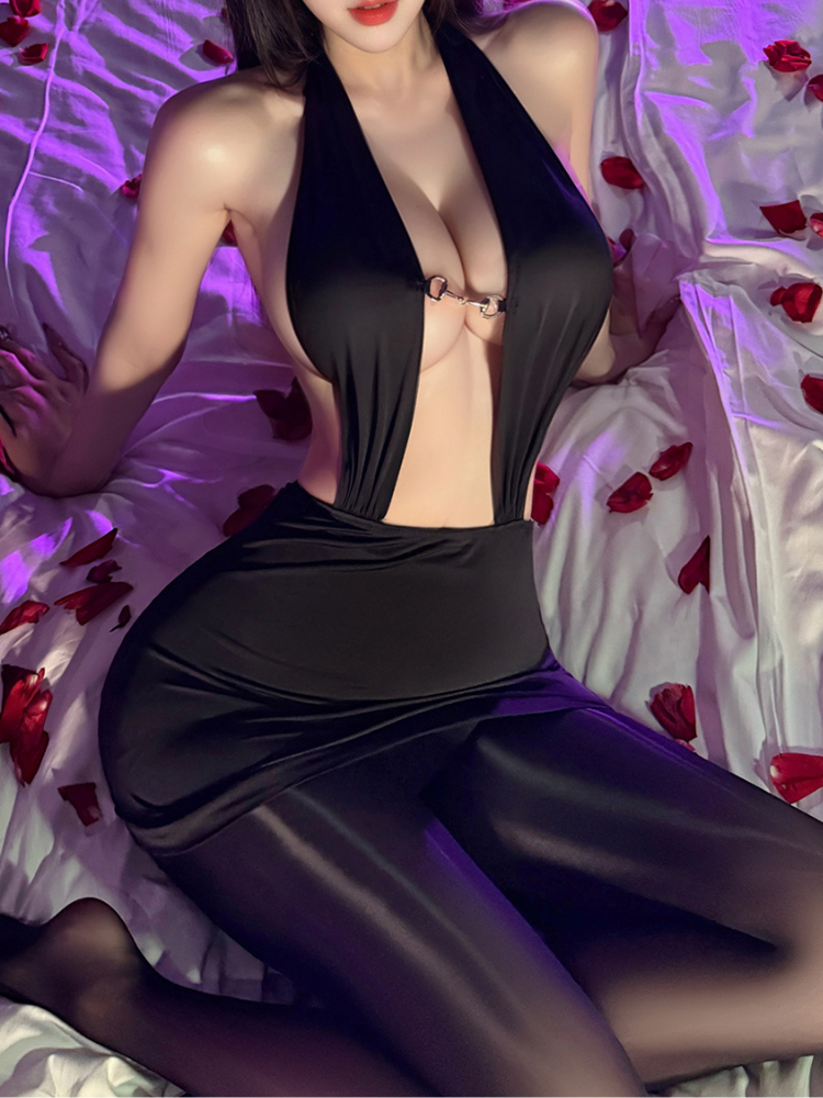 Person wearing a Plunge Halter Ring Detail Black Mini Dress Bodysuit on a bed with red flower petals.