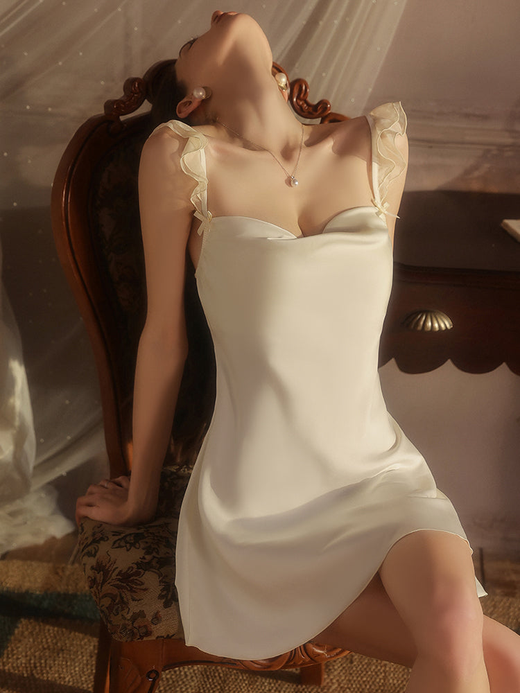 Woman in a white dress lying on a wooden chair with a soft, warm light.