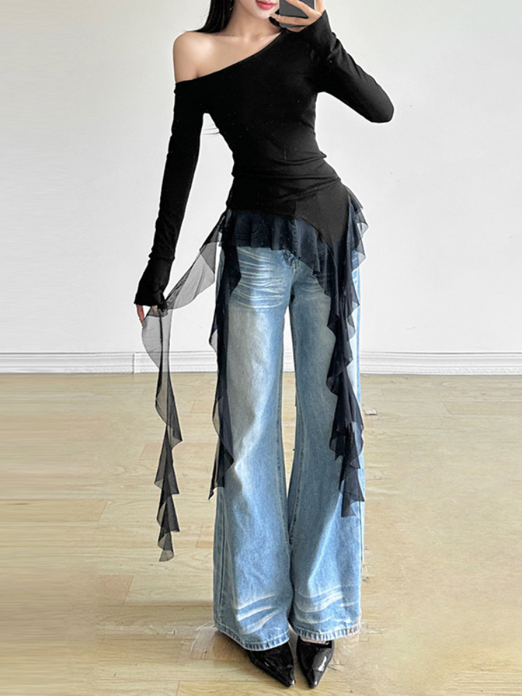 Person wearing a black off-shoulder top and blue jeans with ruffled details on a white background