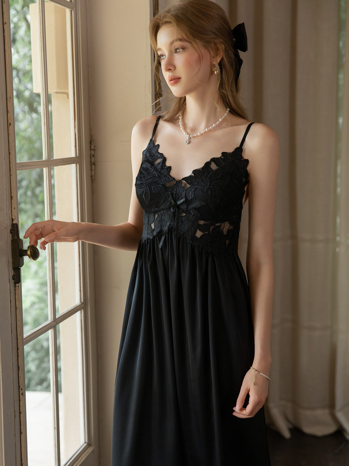 Black satin slip dress front detail showing floral guipure lace bodice, V neckline and bow