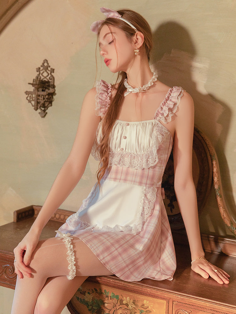 Woman wearing a Pink Plaid Lace Maid Babydoll Mini Dress with ruffles and plaid pattern, sitting on a wooden surface.