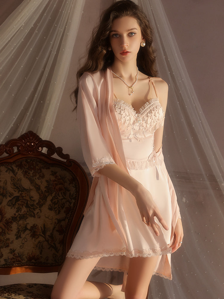Woman in a pink Fringe Lace Satin Mini Slip Dress and robe standing in a softly lit room.