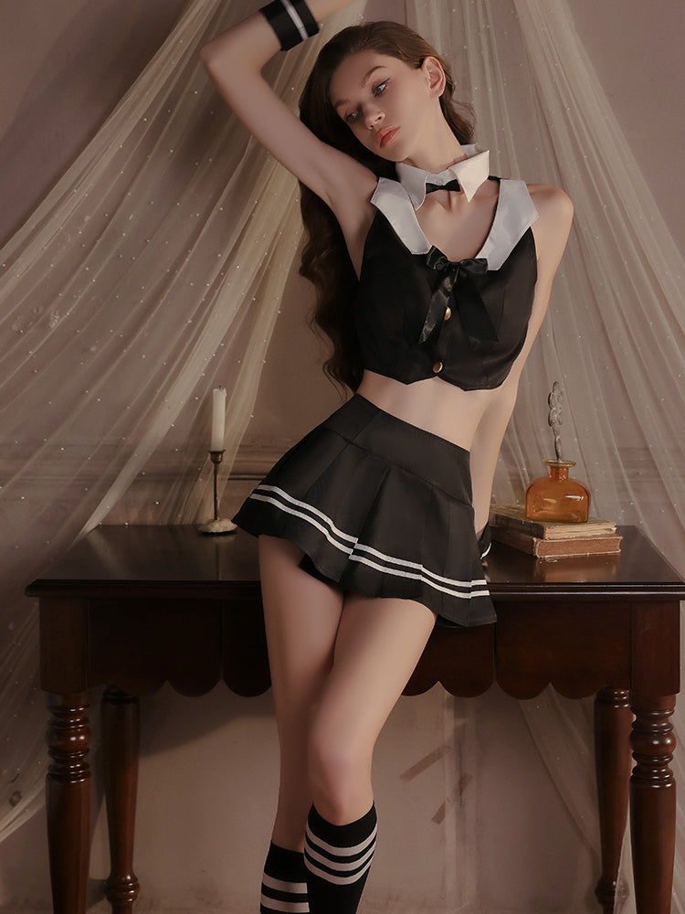 Black and white satin lingerie set styled with striped accents, a bow tie, pleated skirt, and striped socks, posed beside a wooden table.