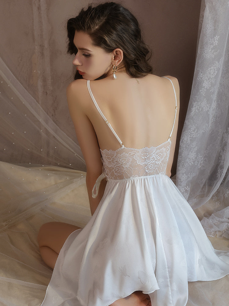 Woman wearing a white Butterfly Lace Appliqué Satin Slip Dress with sheer fabric in a soft, draped setting.