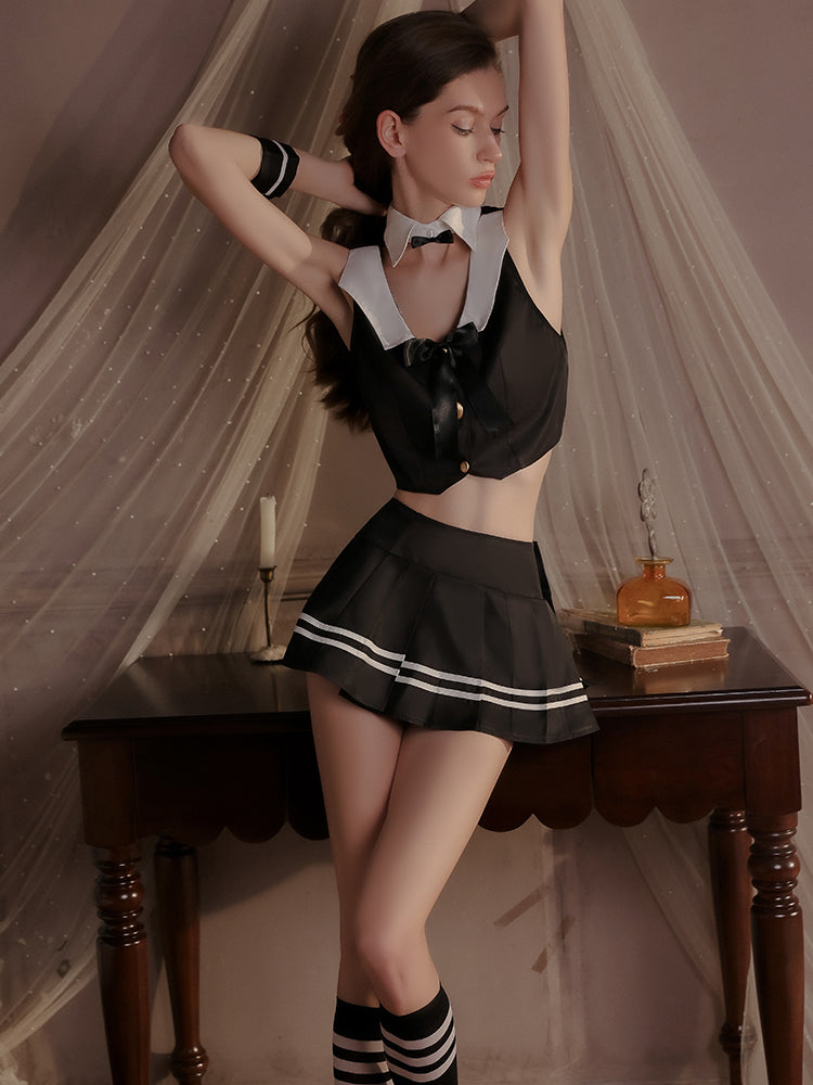 A black satin lingerie set with a cropped top, pleated mini skirt with white stripes, and matching striped accessories against a soft background.