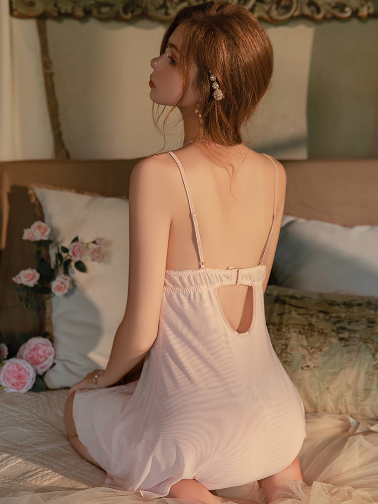 Woman in a light pink dress sitting on a bed with floral decorations.