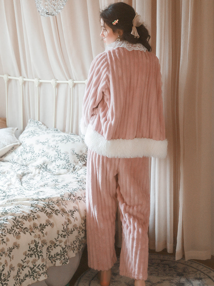Woman in a pink plush robe standing in a bedroom with floral bedding and curtains.