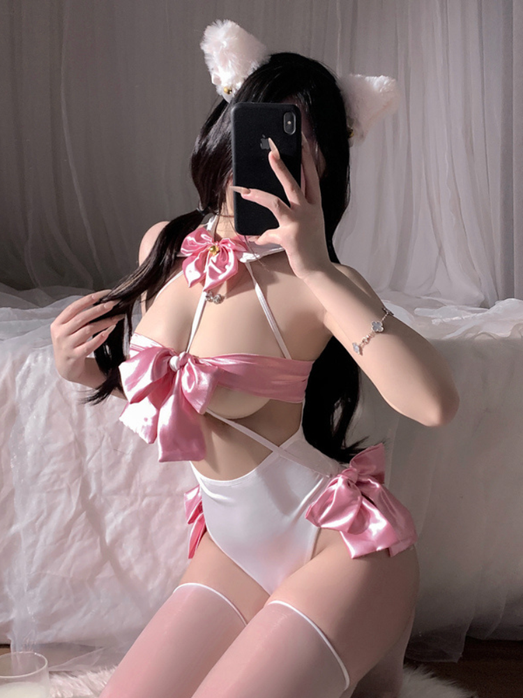 Person wearing a pink and white Satin Bow Halter Lingerie Bodysuit Pink custome with cat ears, sitting on a bed.