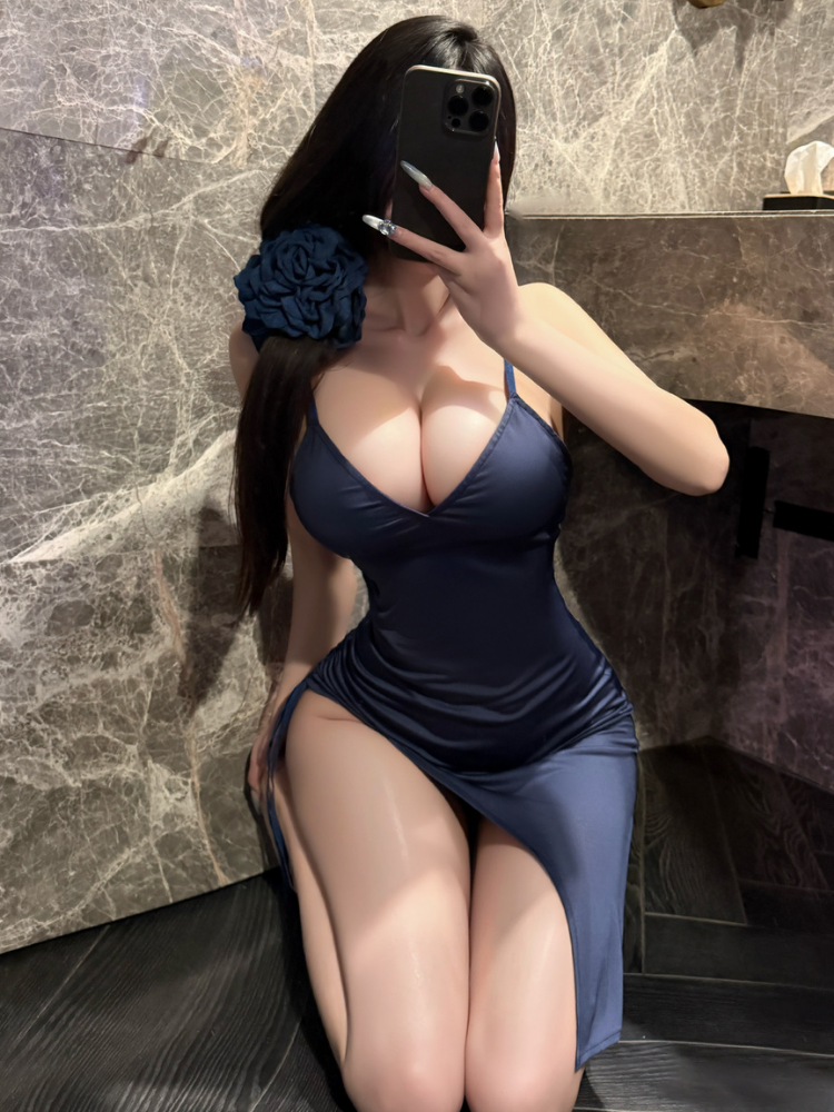 Woman in a Asymmetrical Ruched Satin Slip Dress Navy Blue Mini Dress taking a mirror selfie in a bathroom.