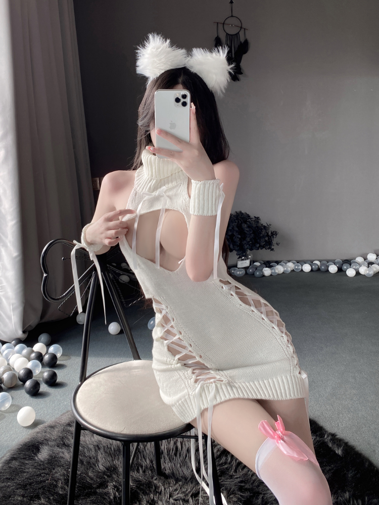 Woman taking a mirror selfie wearing a white Cut Out Lace Up Knit Halter Mini Dress in a room with decorative lights on the floor.