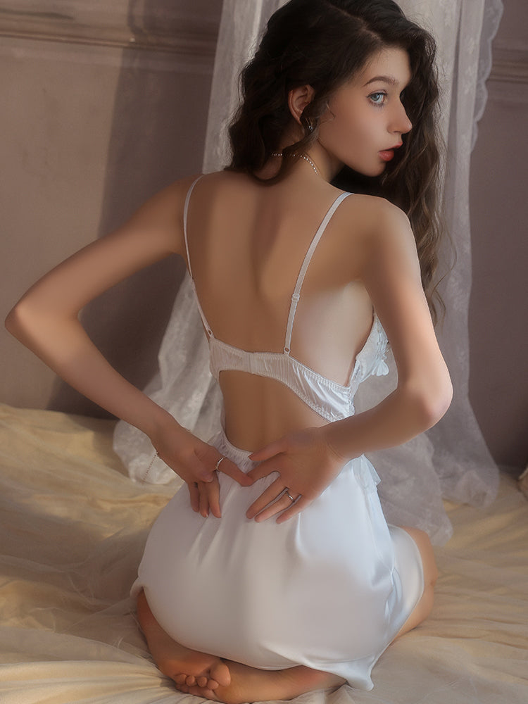 Woman wearing a white Fringe Lace Satin Mini Slip Dress sitting on a bed.