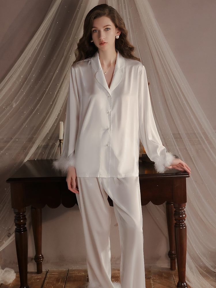 Elegant white satin pajama set with feather trimmed cuffs, perfect for a high end loungewear.