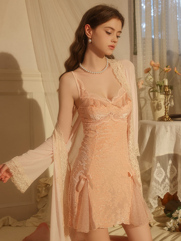 Woman wearing a pink Velvet Floral Satin Slip Dress with Lace and Bow Details with a sheer overlay in a softly lit room.