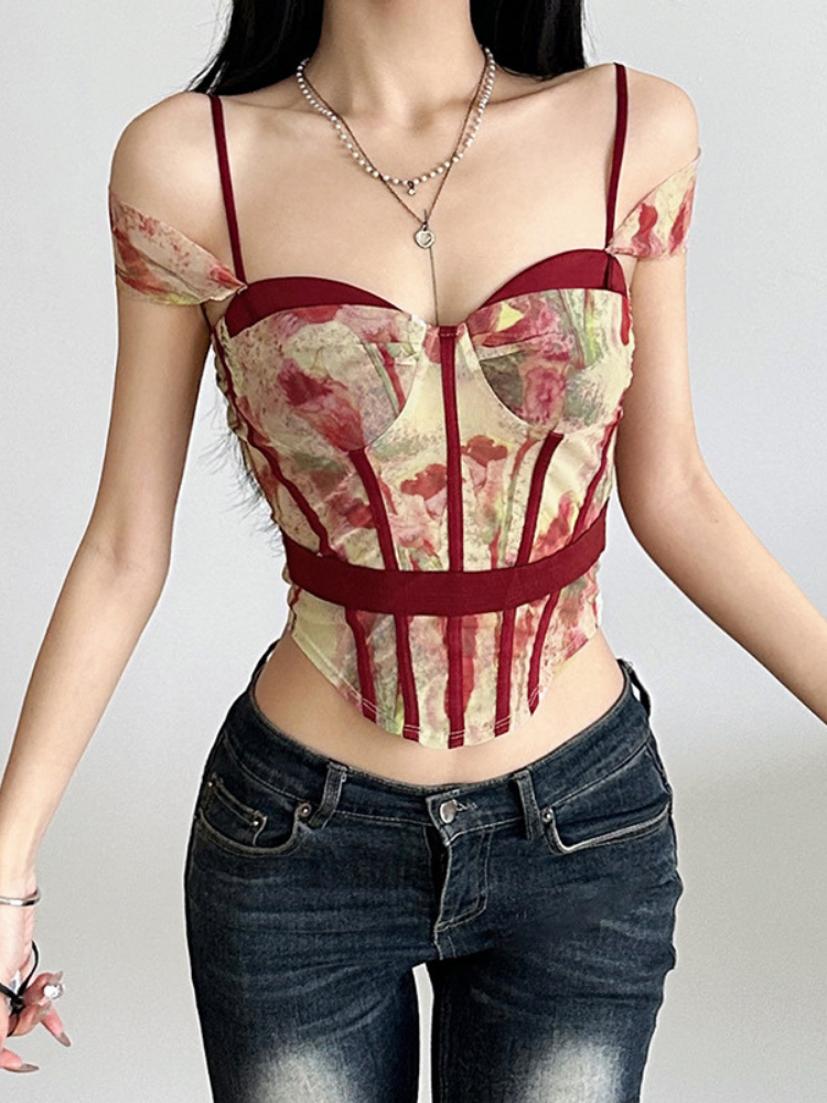 Person wearing a patterned top with red straps and jeans on a plain background