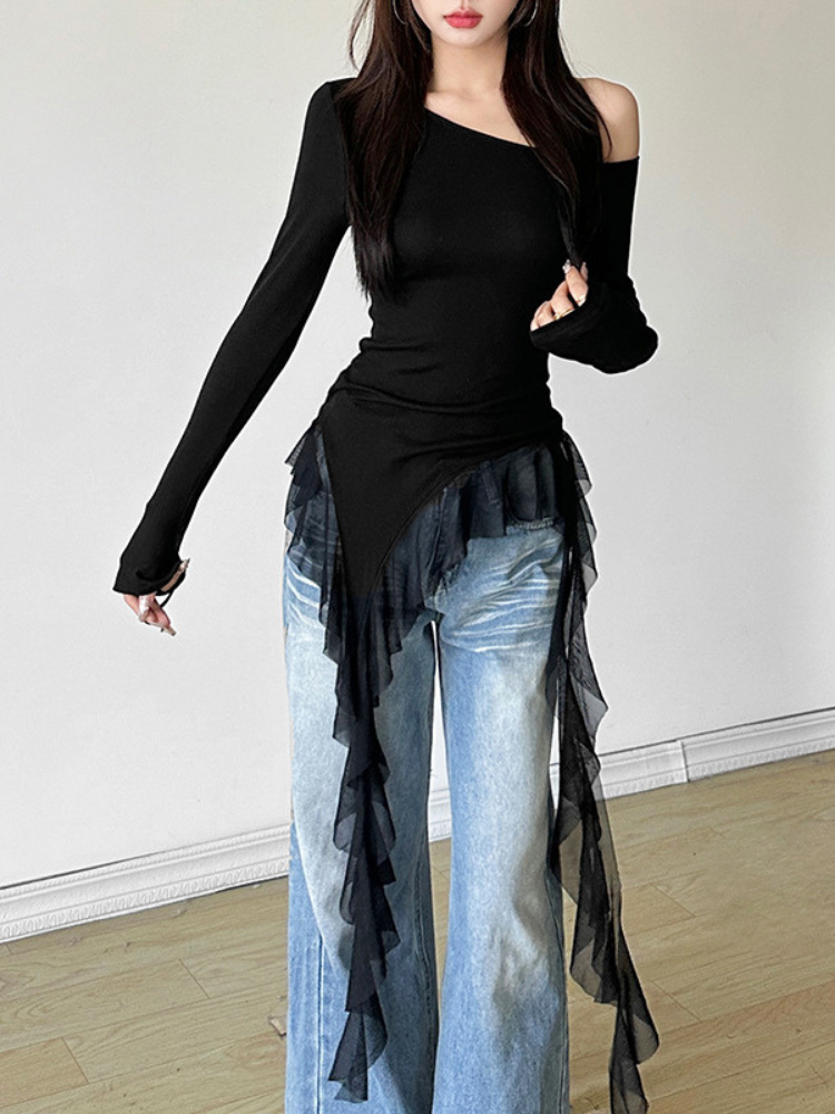 Person wearing a black off-shoulder top and light blue jeans with a sheer black overlay.