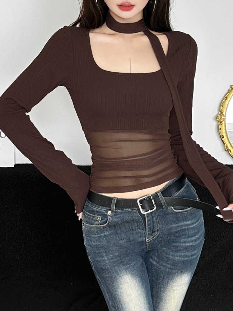 Person wearing a brown long-sleeve top with mesh panels and blue jeans.