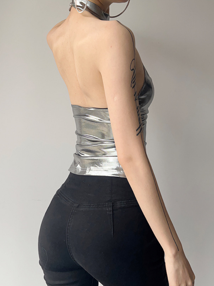 Person wearing a silver strapless top and black pants against a plain background