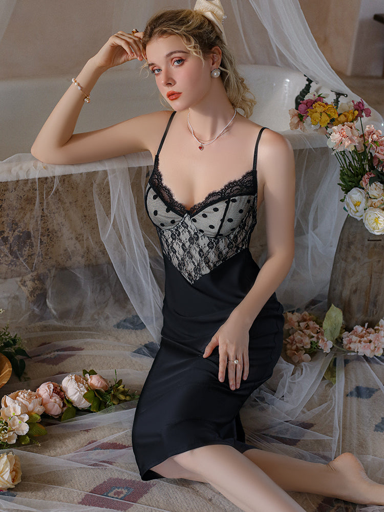 Woman in a Lace Bodice Satin Midi Slip Dress Black sitting in a decorated room with flowers.