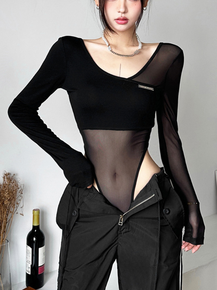 Person wearing a black sheer top and black pants with a white background