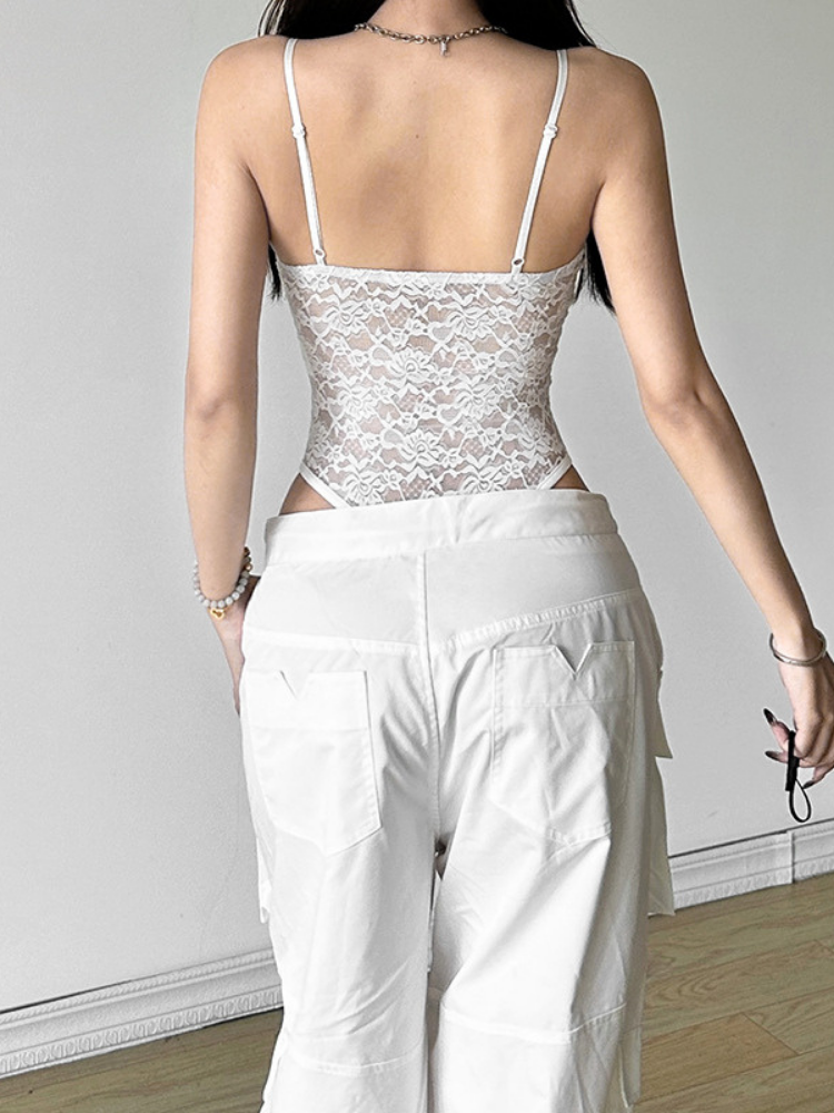 Person wearing a white lace top and white pants against a plain background