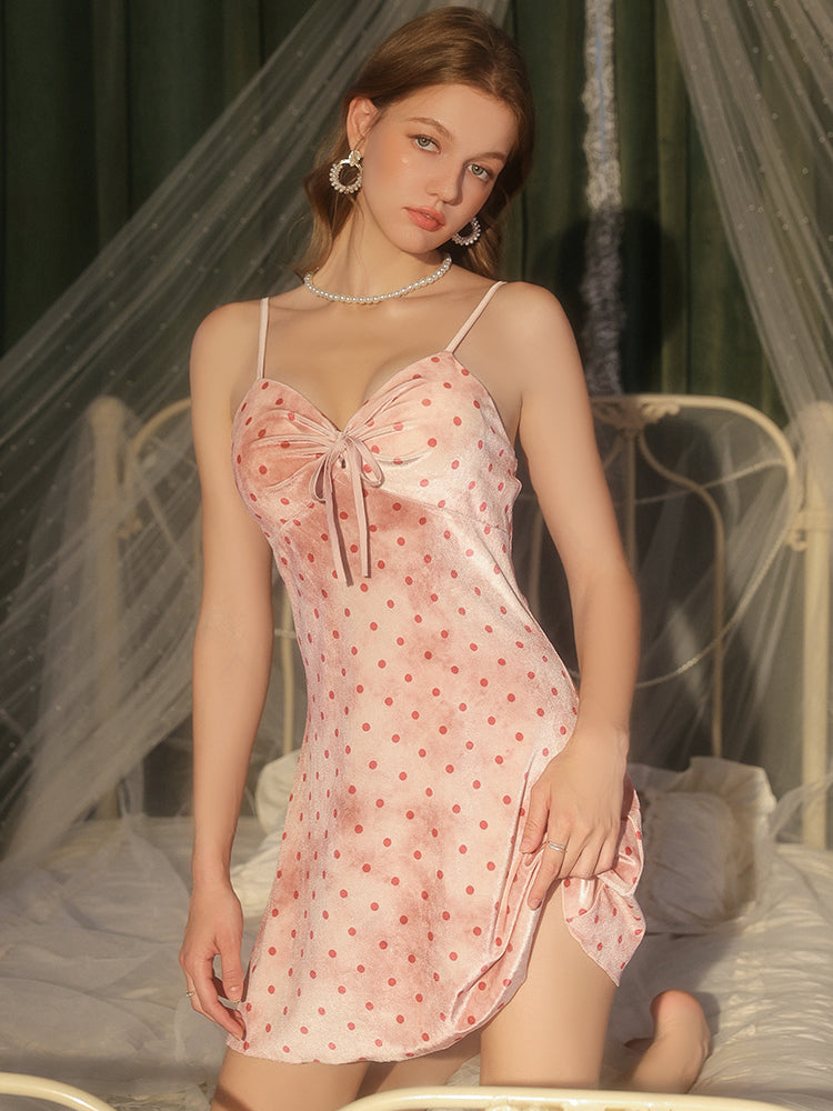 Woman wearing a pink polka dot nightgown in a softly lit room.